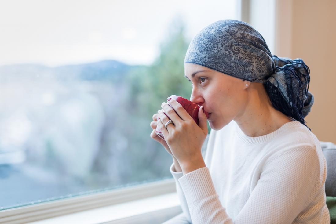 Cancer patient looking out of window drinking from mug