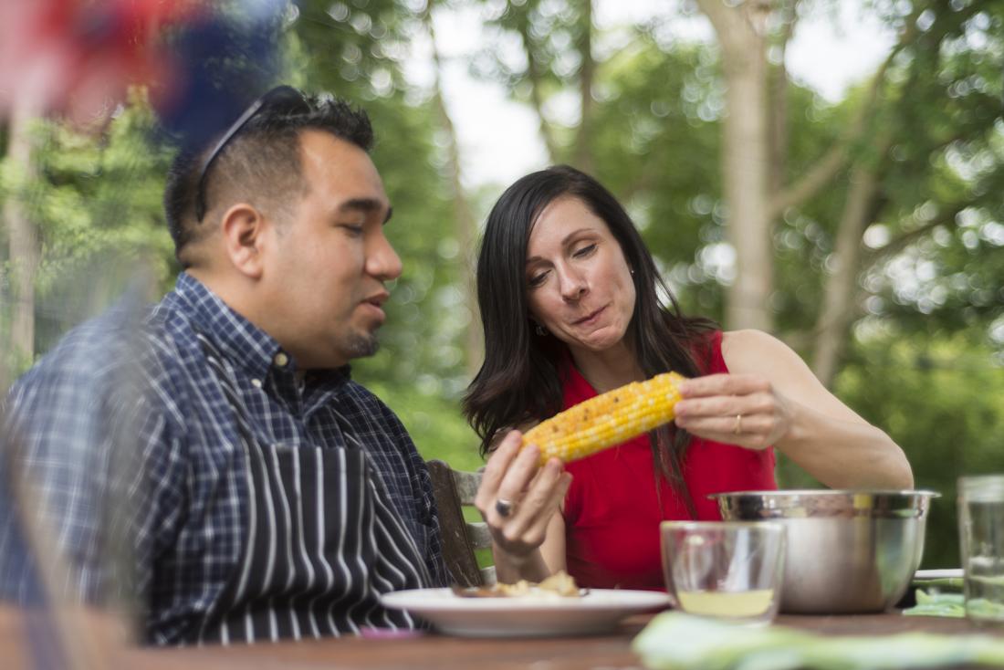 People eating corn on the cob at outdoor BBQ