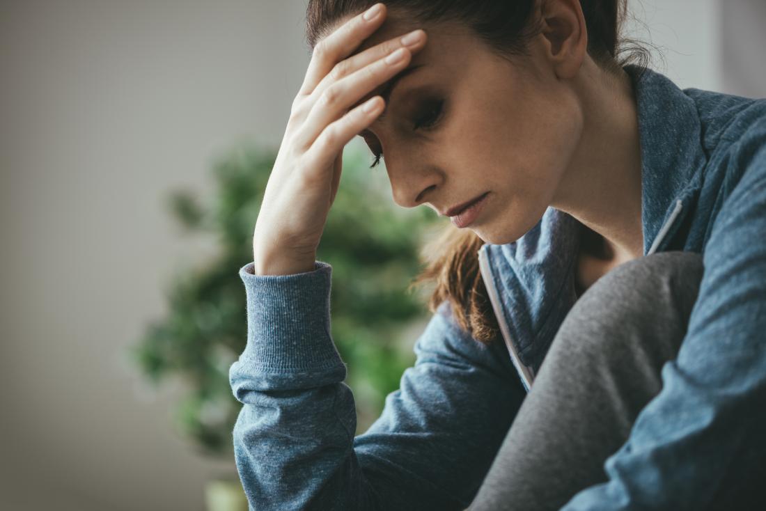 woman with endometrial fatigue holding head and looking tired and sad