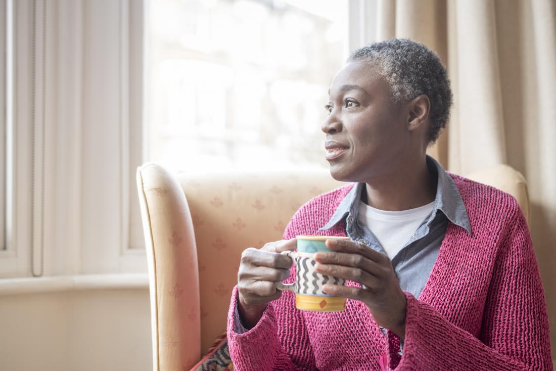 mature woman holding cup and looking out of window