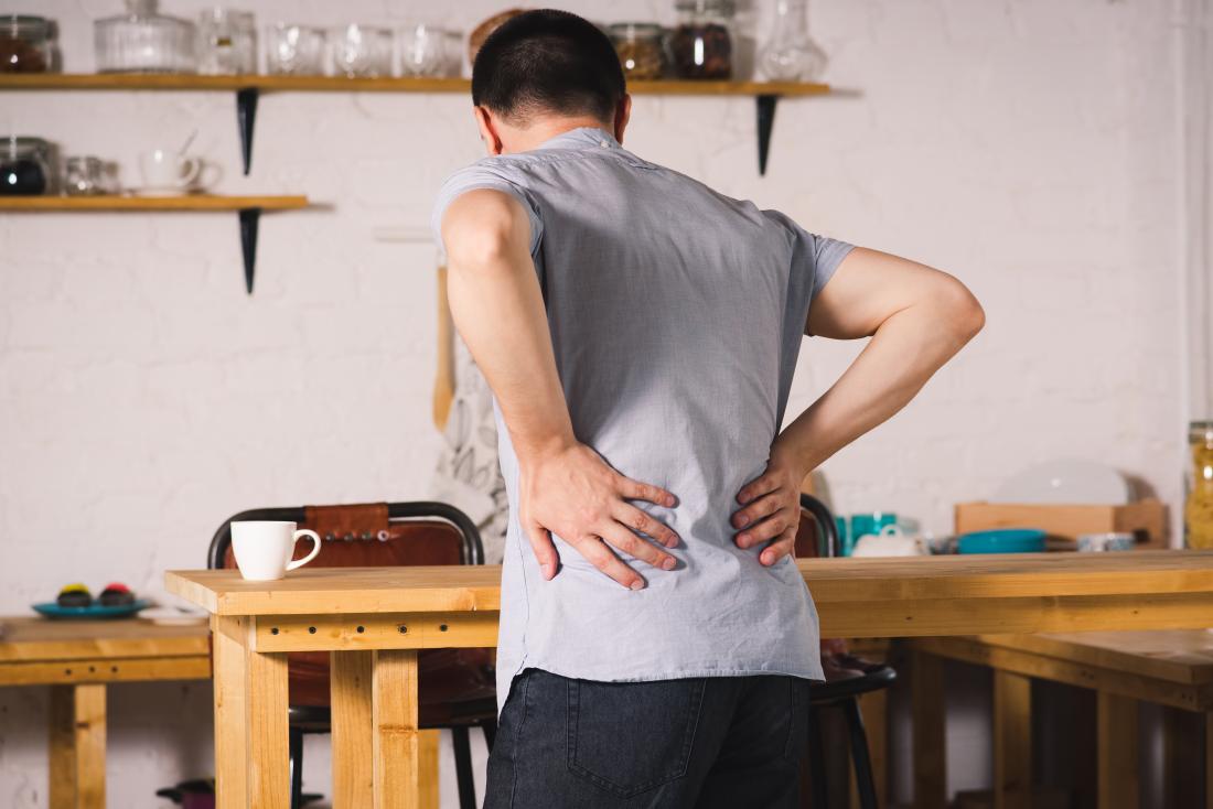 man in kitchen holding his lower back