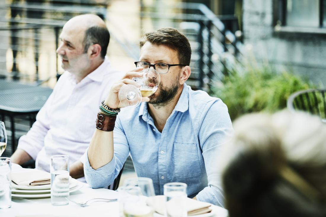 Man drinking beer outdoors at dining table