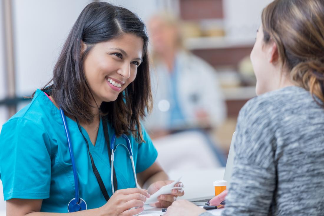 Female doctor in scrubs discussing prescription with patient.