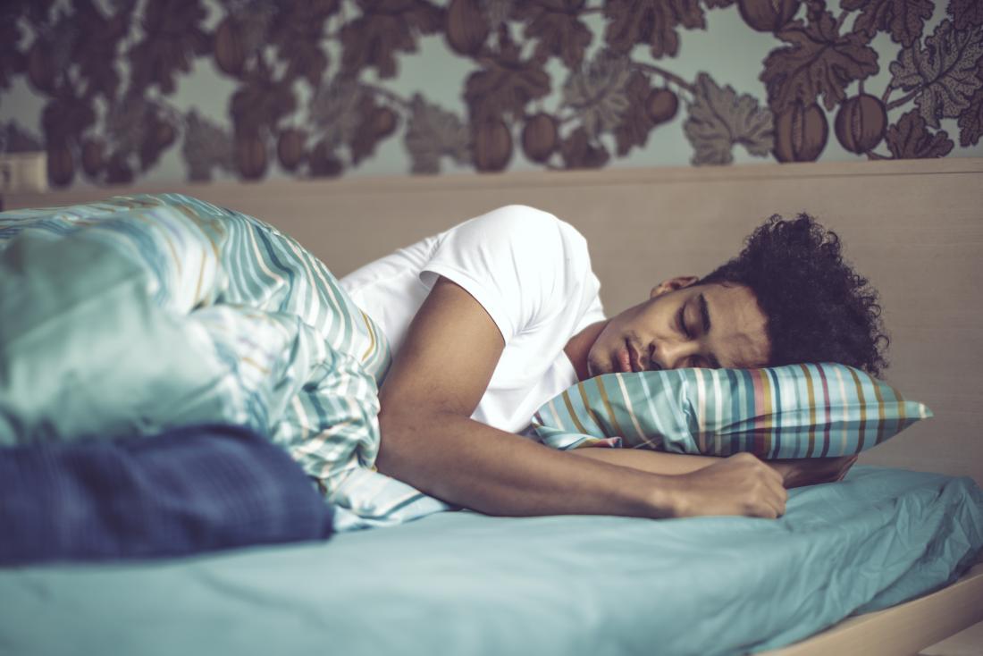 Young man sleeping on bed.