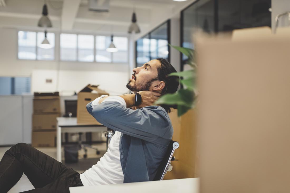 Man leaning back on desk chair holding neck