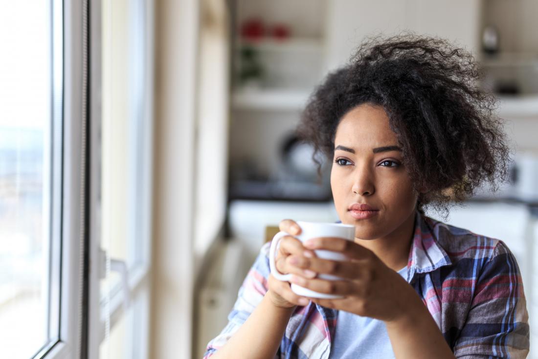 Thoughtful woman sitting down drinking tea