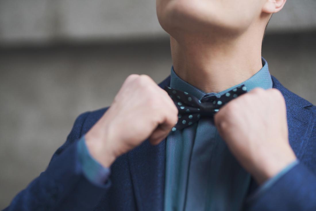 Man with adam's apple tying bow tie