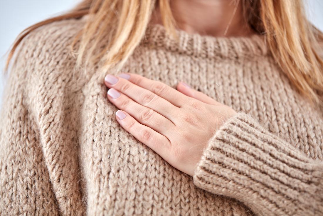 Woman with sore breast pain holding hand over chest